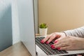 Home office. Open laptop on the table. Caucasian woman with red manicure taping on notebook Royalty Free Stock Photo