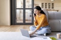 Home Office. Smiling Young Indian Woman Using Laptop And Talking On Cellphone Royalty Free Stock Photo