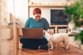 Woman works online using laptop computer, dog interferes. Quarantine coronavirus