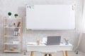 Home office for work or hobby. On white table are laptop with cup and notepads, board in back with empty space Royalty Free Stock Photo