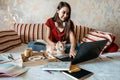 Home office, work space, work from home concept. Young woman with laptop and cat working at sofa. Flexible work hours Royalty Free Stock Photo