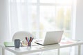 Home office. Workplace with white laptop, notes and cup of tea on the table at home. Bright light coming from the window Royalty Free Stock Photo