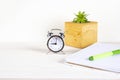 Home office workspace mockup with notebook, pen, alarm clock, plant in wooden potted and accessories on white wood desk background Royalty Free Stock Photo