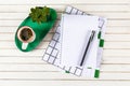 Home office workspace mockup with notebook, pen, cup of coffee,  plant potted on green tray and accessories on white wood desk Royalty Free Stock Photo