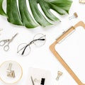 Home office workspace mockup with tropical leaves Monstera, clipboard, and accessories on white background. Flat lay Royalty Free Stock Photo