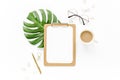 Home office workspace mockup with tropical leaves Monstera, clipboard, and accessories on white background. Flat lay Royalty Free Stock Photo