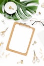 Home office workspace mockup with tropical leaves Monstera, clipboard, and accessories on white background. Flat lay Royalty Free Stock Photo