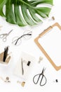 Home office workspace mockup with tropical leaves Monstera, clipboard, and accessories on white background. Flat lay Royalty Free Stock Photo