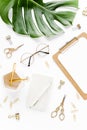 Home office workspace mockup with tropical leaves Monstera, clipboard, and accessories on white background. Flat lay Royalty Free Stock Photo