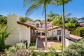 a house surrounded by palm trees and landscaping with a covered front porch Royalty Free Stock Photo