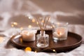 Home perfume in glass bottle with wood sticks, scented burn candles tray in bedroom close up. Aromatherapy cozy atmosphere lifest