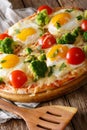 Home pizza with eggs, broccoli, tomatoes and greens close-up. vertical