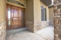 Home porch and brown wood front door with sidelights and arched transom window