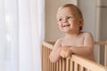 Home portrait of cute little baby boy in bed with pensive face looking at copy space