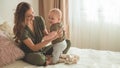 Home portrait of a baby boy with mother on the bed. Mom holding and kissing her child. First Steps.