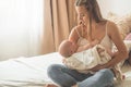 Home portrait of a newborn baby with mother on the bed. Mom holding and kissing her child. Royalty Free Stock Photo