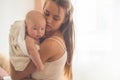 Home portrait of a newborn baby with mother on the bed. Mom holding and kissing her child. Royalty Free Stock Photo