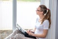 Home quarantine. Remote work at home. Caucasian woman sitting at window with a computer.Counts on calculator and writes Royalty Free Stock Photo