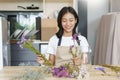 Home relaxation concept, Young woman sitting in kitchen room and arrange flowers in vase on table