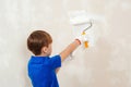 Home renovation. Boy having fun during home renovation. Young boy painting interior wall with paint roller