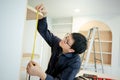 Asian male furniture assembler using tape measure Royalty Free Stock Photo