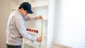 Asian male furniture assembler using tape measure on cabinet