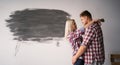 Home renovation and relationships concept. Loving couple hug near their freshly painted wall in room. Copy space. Royalty Free Stock Photo