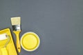 Home renovation and repair concept. paintbrush, sponge roller and can of yellow paint on gray background Royalty Free Stock Photo