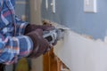 Home renovation service works on worker cutting plasterboard with construction electric power tools of replacement damaged drywall