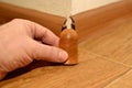 Worker with a hand installs the corner of the baseboard