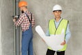 home repairs. Two young man architect with blueprint and builder with level near wall on a building construction site Royalty Free Stock Photo