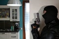 Home robbery by a man with black balaclava and gun in hand hiding behind the wall. Royalty Free Stock Photo