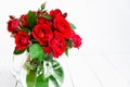 Home roses in a glass vase on a white wooden table. With copy space Royalty Free Stock Photo