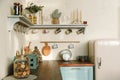 Home rustic kitchen interior: wooden countertop with retro fridge, shelves with mugs and utensils, soft pastel colors. Royalty Free Stock Photo