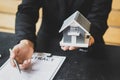 A home salesman is holding a gray small house model and explaining the property purchase contract. Royalty Free Stock Photo