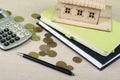 Home savings, budget concept. Model house, notepad, calculator,pen and coins on wooden office desk table. Royalty Free Stock Photo