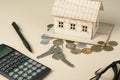 Home savings, budget concept. Model house, notepad, pen, calculator and coins on wooden office desk table. Royalty Free Stock Photo