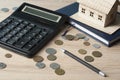 Home savings, budget concept. Model house, notepad, pen, calculator and coins on wooden office desk table. Royalty Free Stock Photo