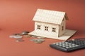 Home savings, budget concept. Model house, notepad, pen, calculator and coins on wooden office desk table. Royalty Free Stock Photo