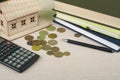 Home savings, budget concept. Model house, notepad,, calculator,pen and coins on wooden office desk table. Royalty Free Stock Photo