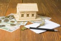 Home savings, budget concept. Model house, pen, keys notepad and money on wooden office desk table. Royalty Free Stock Photo