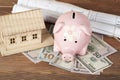 Home savings, budget concept. Model house, piggy bank,money on wooden office table.