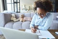 Home Schooling. Concentrated mixed race teen girl in glasses doing homework, studying in the living room at home during