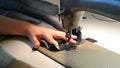 Home seamstress sews. Female hands sew jeans. A sewing machine works.