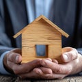 Home security Businessmans hand covers and safeguards wooden home model Royalty Free Stock Photo