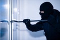 Robber in black balaclava cracking door with crowbar Royalty Free Stock Photo