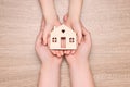 Home security concept. Man with his little child holding house model at wooden table, top view Royalty Free Stock Photo