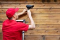 Home security - man installing outdoor surveillance camera on wooden wall copy space