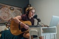 Home sound studio young teenager portrait playing guitar in Headphones recording voice music using a microphone and laptop Royalty Free Stock Photo