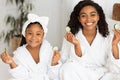 Home Spa. Beautiful African Mother And Daughter In Bathrobes Holding Cucumber Slices Royalty Free Stock Photo